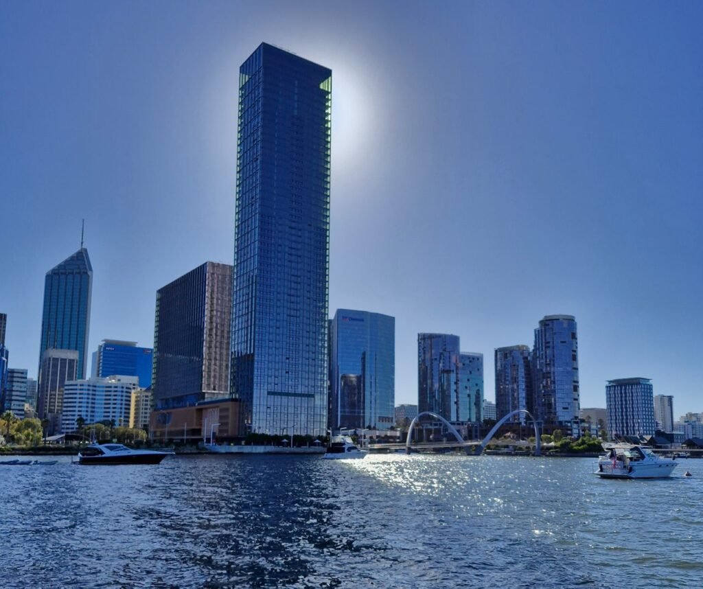 Stunning view of Perth skyline with sunlit skyscrapers reflecting on the Swan River.